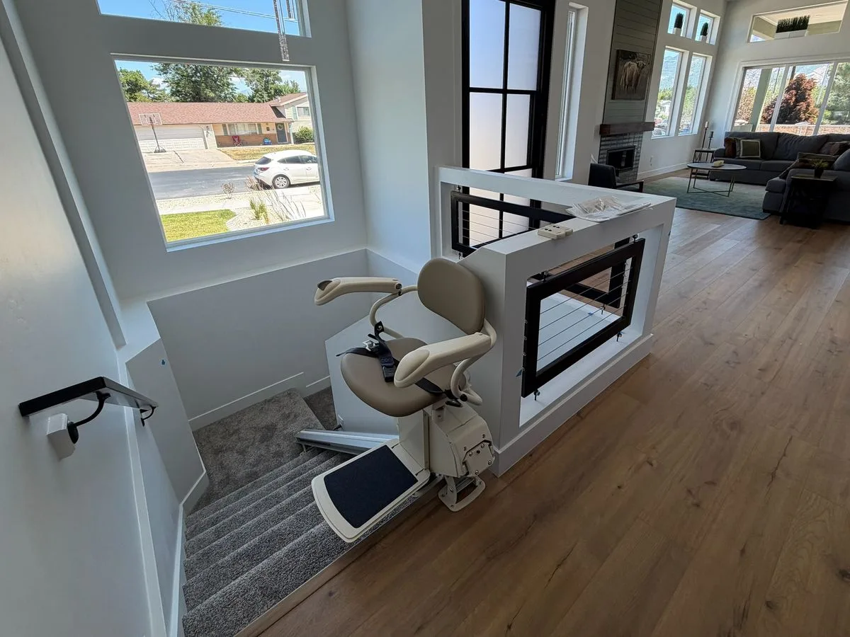 The same staircase with a tan stairlift, seat and footrest open at the upper landing